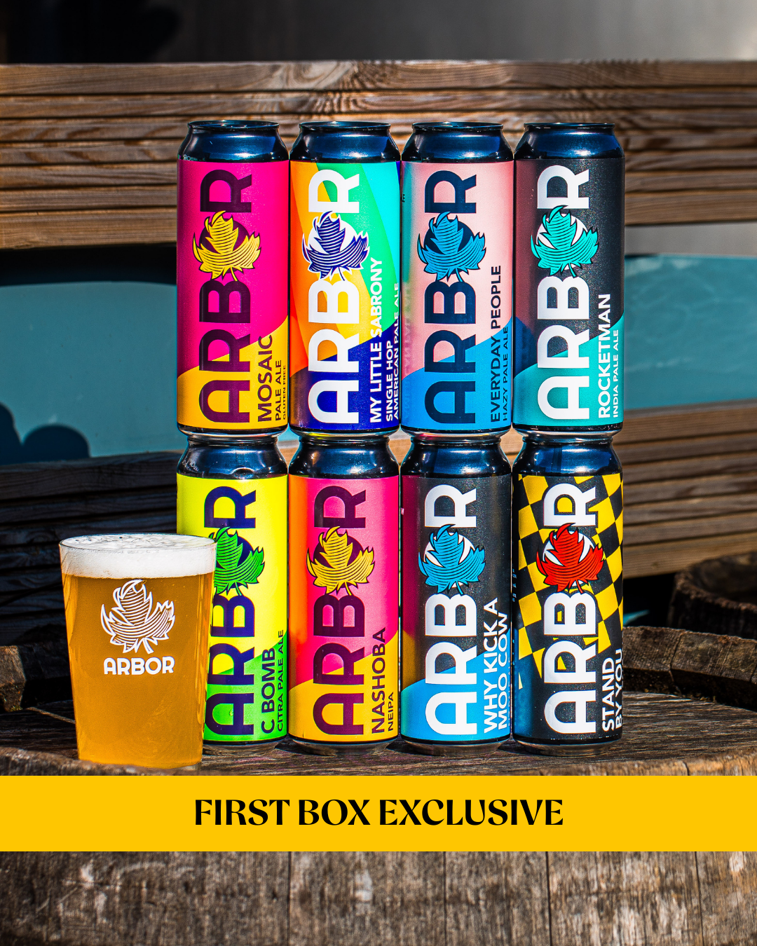 Assorted Arbor Brewing cans and a glass of beer on a wooden surface.