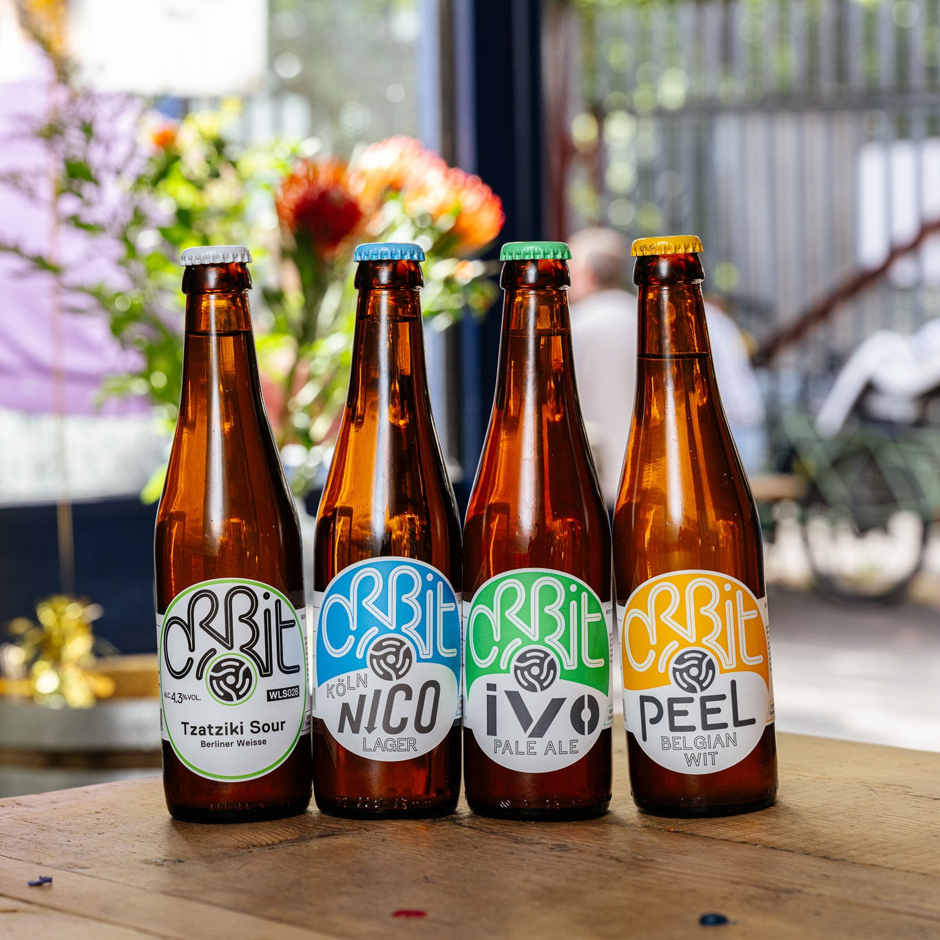 Orbit Beers bottles with Tzatziki Sour, Nico, Ivo and Peel on a patio table, Brewser craft beer subscription