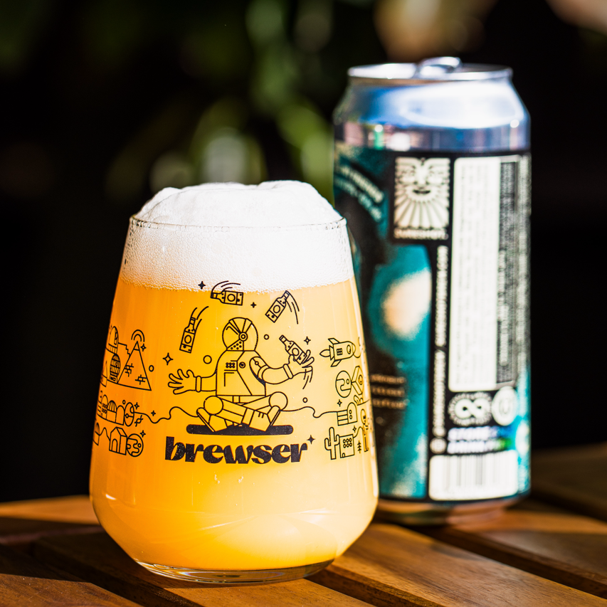Poured Brewser glass of beer beside a Lost and Grounded Brewers can on wood, craft beer subscription lifestyle