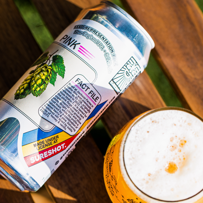 Sureshot Brewing Pink New England IPA can close-up with a poured glass on wood, Brewser craft beer subscription