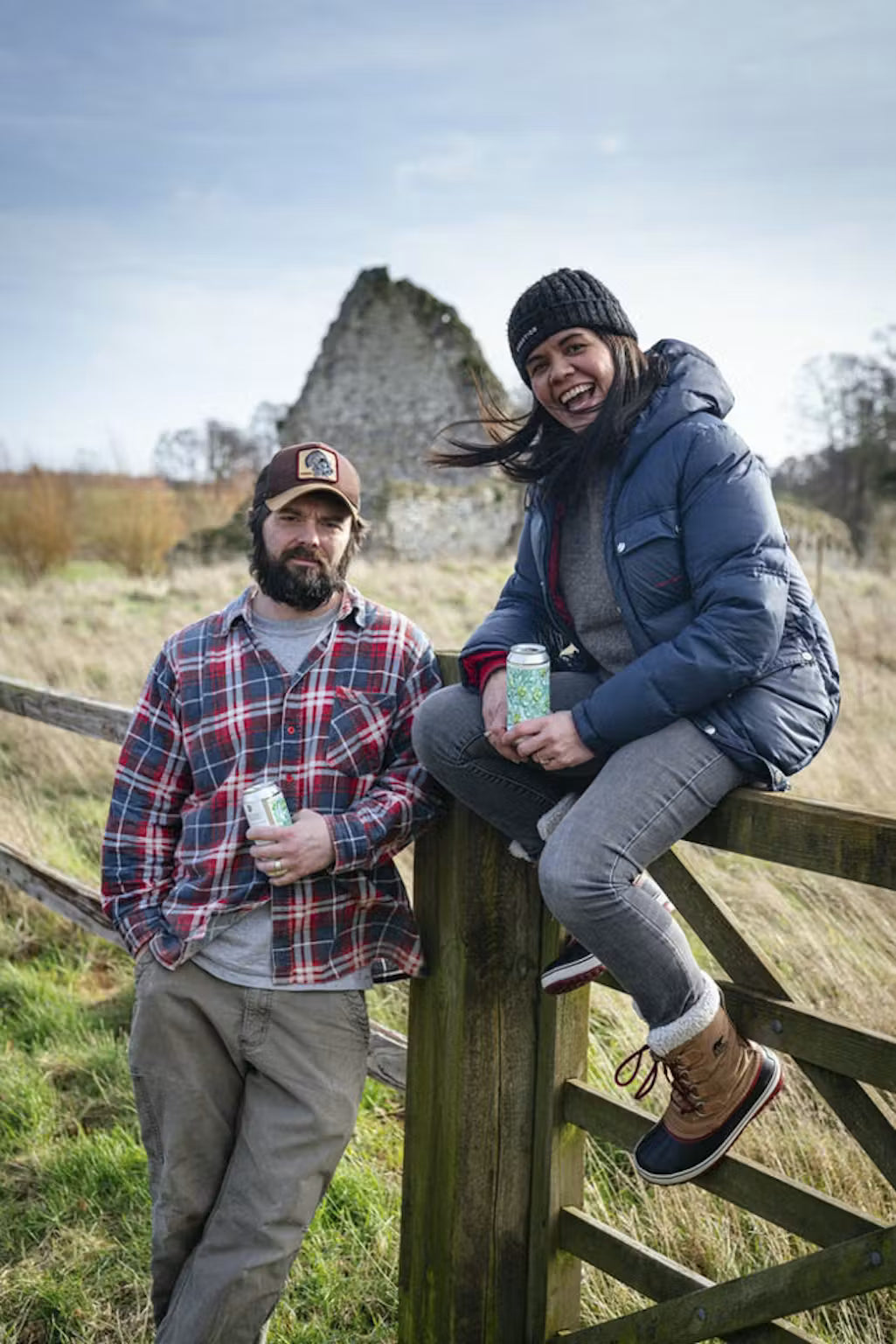 Two people outdoors by a gate holding Orbit Beers cans, Brewser craft beer subscription lifestyle