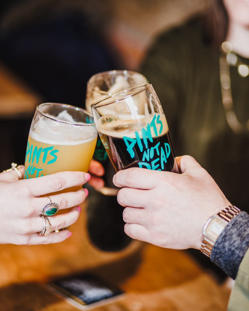 Two people clinking Courier Brewing "Pints Not Dead" glasses in a cheers, Brewser craft beer subscription lifestyle
