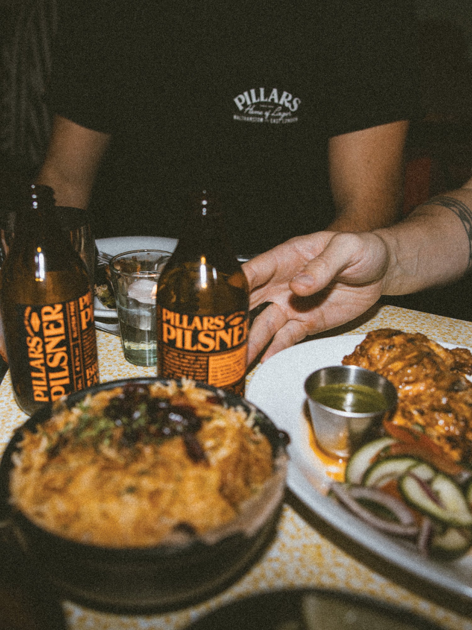 Two Pillars Brewery Pilsner bottles on a dinner table with food, Brewser craft beer subscription meal