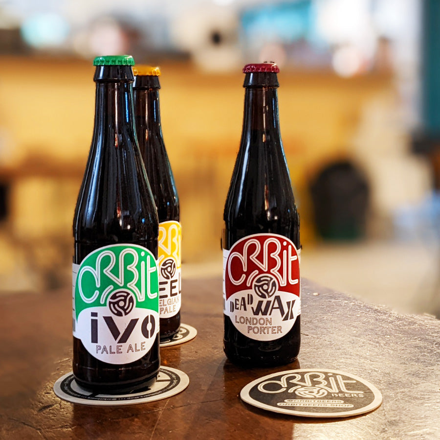 Orbit Beers bottle lineup with Ivo Pale Ale, Peel and Dead Wax London Porter on a bar, Brewser subscription box