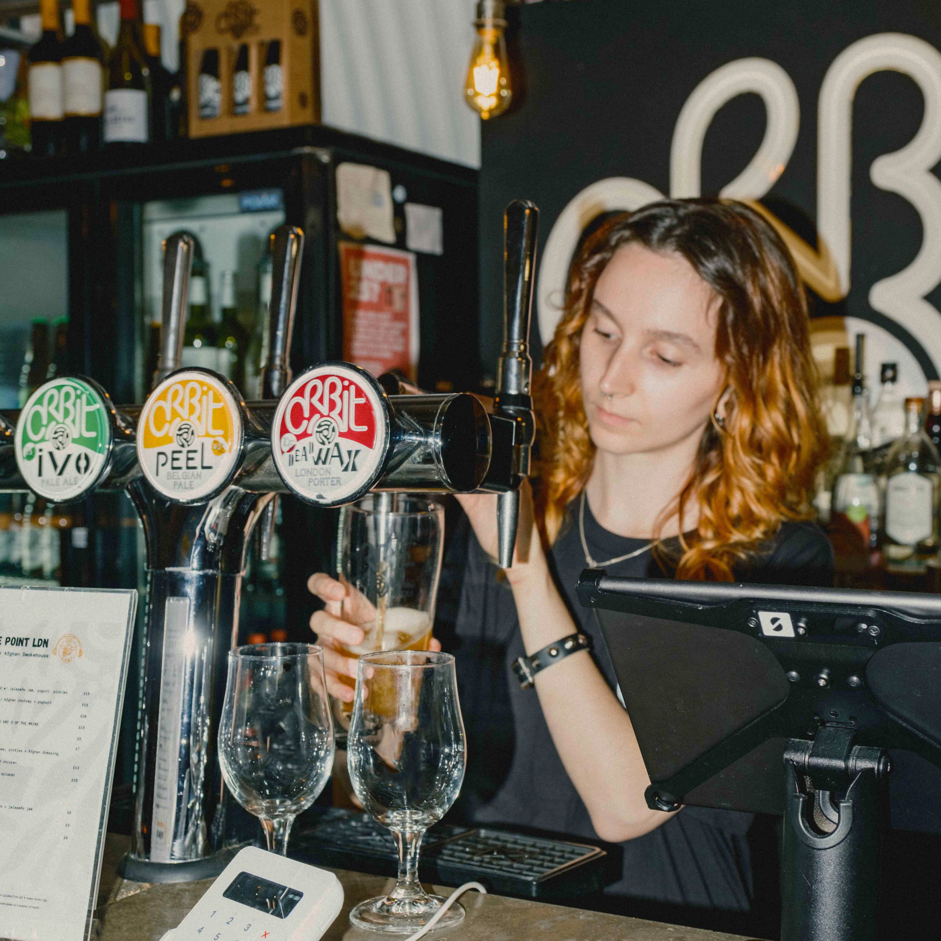 Orbit Beers taproom with a bartender pouring pints from branded taps, a Brewser craft beer subscription partner