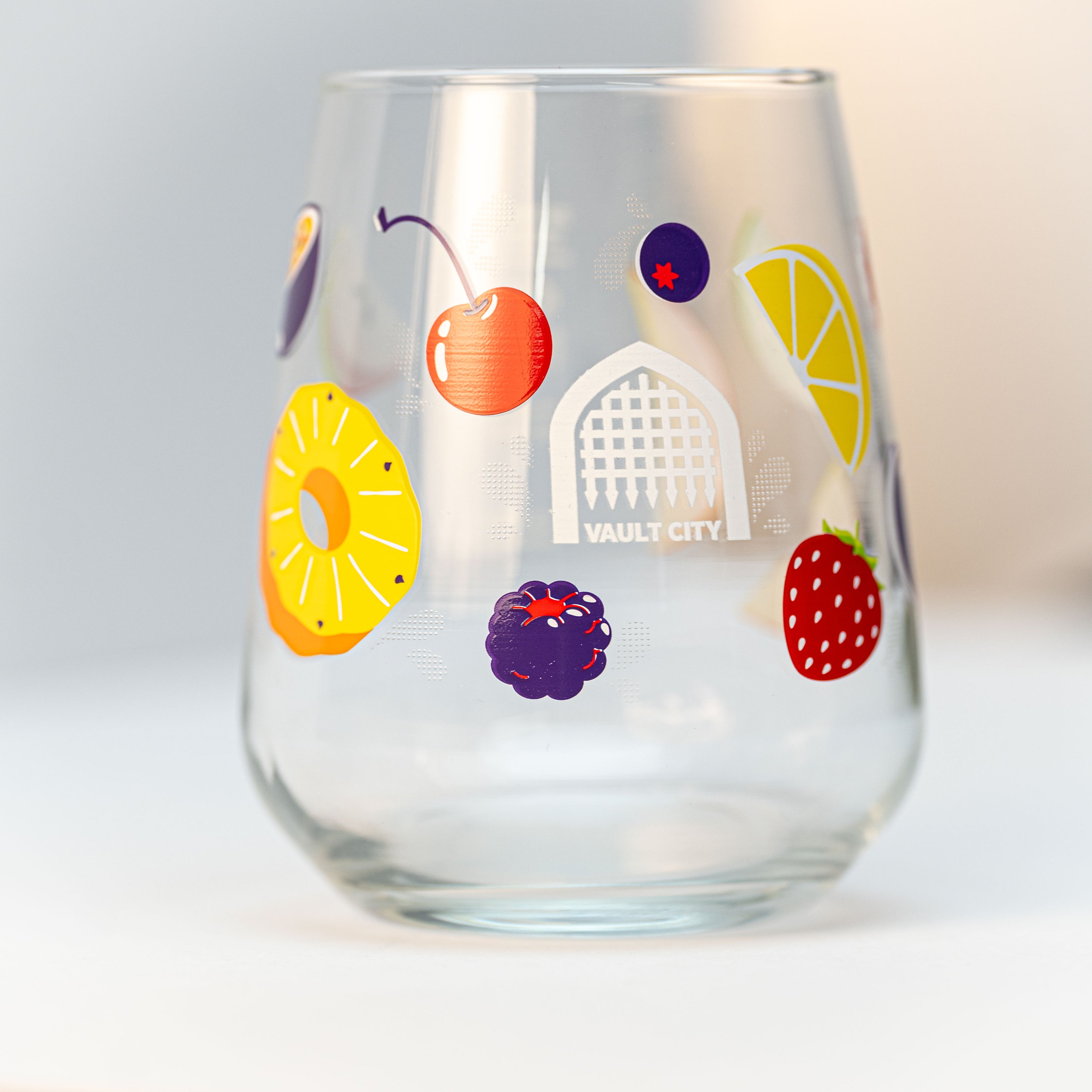 Vault City branded stemless glass with colourful fruit illustrations, part of the Brewser craft beer subscription