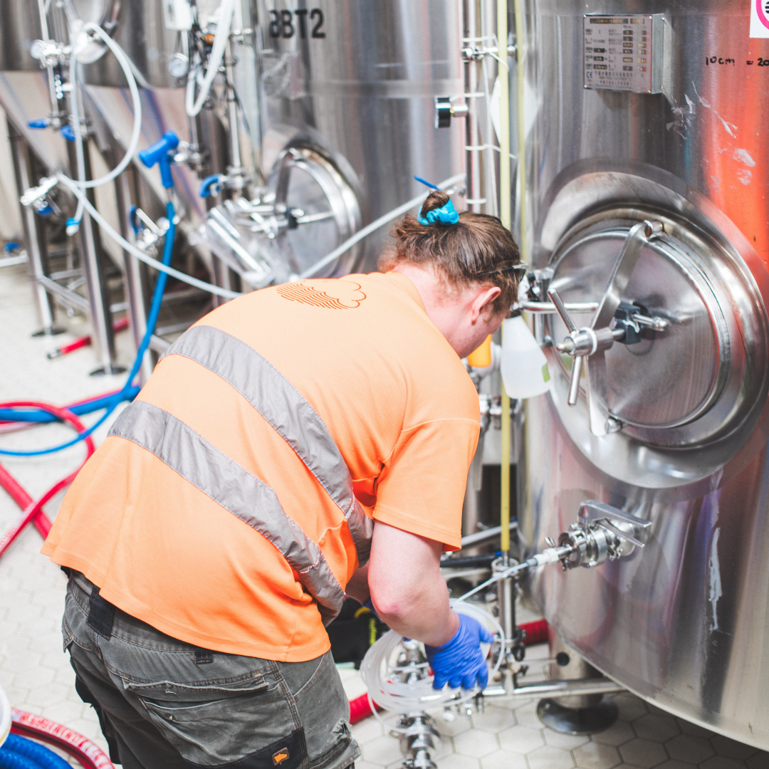 Brewer operating fermentation tank valves at a craft brewery, featured in Brewser subscription box selection